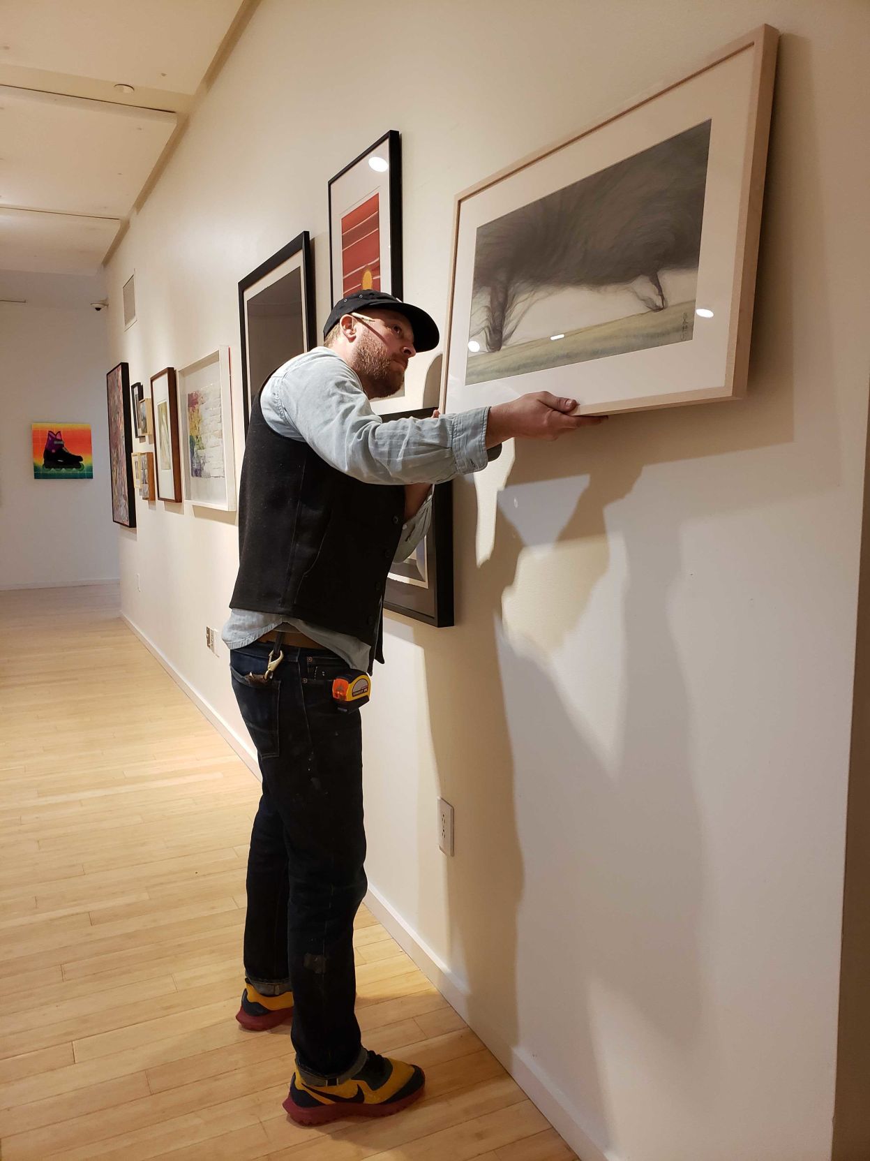 A man hangs a work of art on the wall of an exhibit